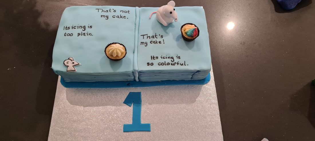 Book-themed birthday cake with cupcakes and fondant mouse